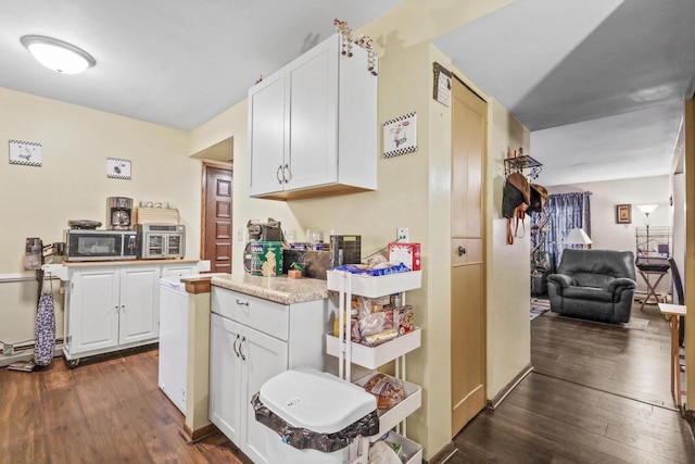 kitchen featuring stainless steel microwave, dark wood-type flooring, white cabinets, and light countertops