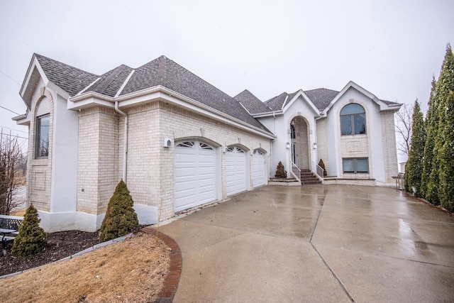 view of front of property with concrete driveway, an attached garage, brick siding, and roof with shingles