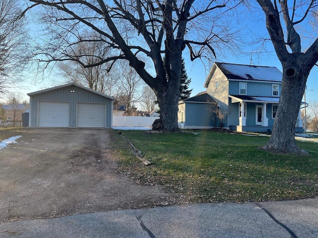 view of property exterior with an outbuilding, a lawn, a detached garage, and fence