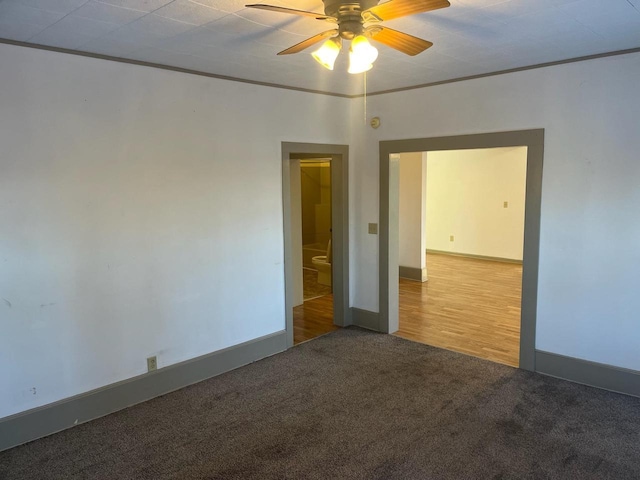 carpeted spare room with baseboards, a ceiling fan, and crown molding