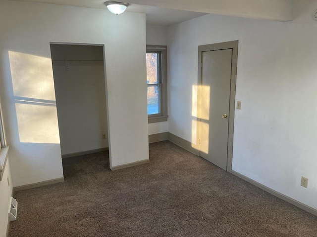 unfurnished bedroom featuring baseboards, visible vents, and dark carpet