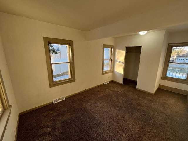 unfurnished bedroom featuring visible vents, baseboards, and dark colored carpet