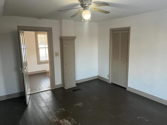 spare room featuring ceiling fan, visible vents, baseboards, and dark wood-style floors