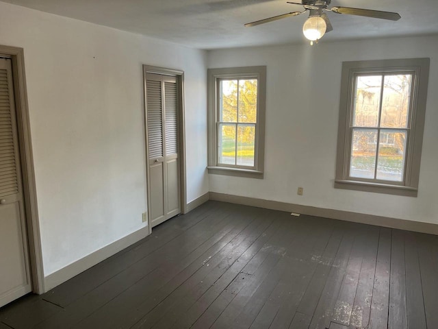 spare room featuring baseboards, dark wood-type flooring, and a ceiling fan