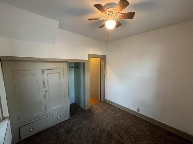 unfurnished bedroom with baseboards, dark colored carpet, a closet, and ceiling fan