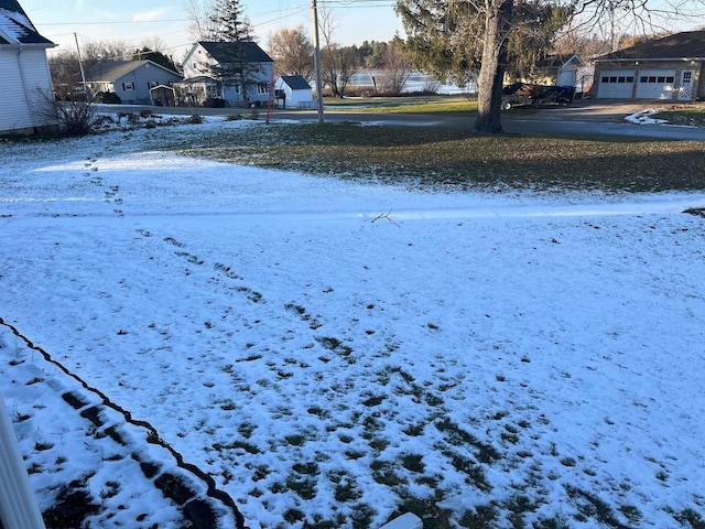 yard covered in snow with a residential view and a detached garage