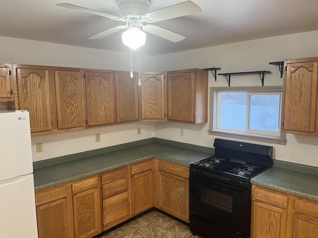 kitchen featuring dark countertops, freestanding refrigerator, brown cabinetry, gas stove, and a ceiling fan