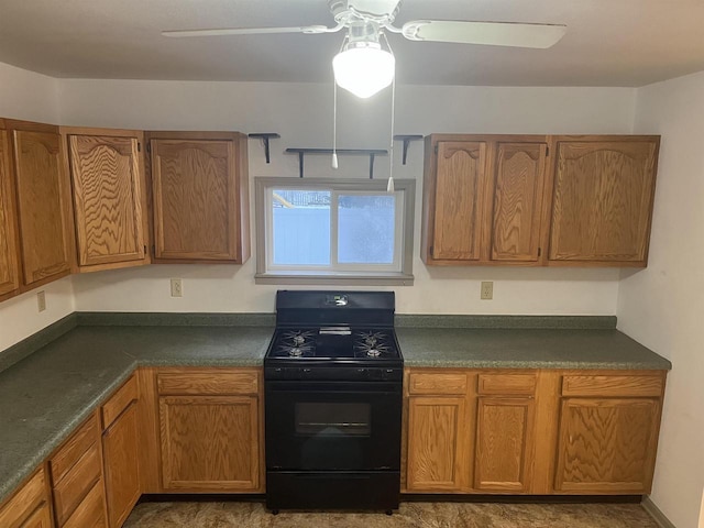 kitchen featuring black range with gas cooktop, brown cabinets, dark countertops, and a ceiling fan