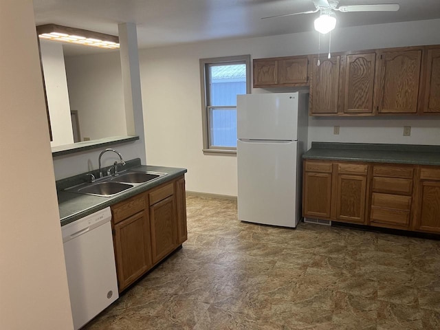 kitchen with white appliances, brown cabinetry, dark countertops, and a sink