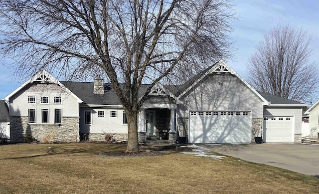 view of front of house featuring a front lawn, stone siding, concrete driveway, an attached garage, and a chimney