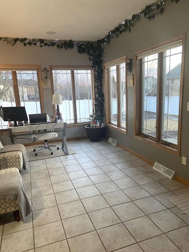 interior space with light tile patterned flooring, visible vents, and baseboards