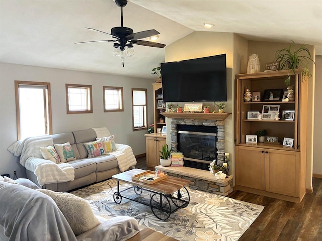 living area featuring ceiling fan, lofted ceiling, a stone fireplace, and dark wood-style floors