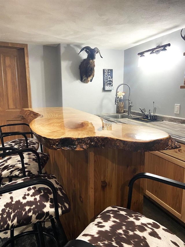 bar featuring indoor wet bar, a textured ceiling, and a sink