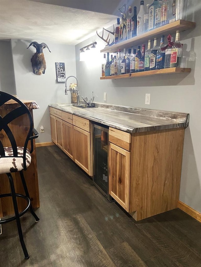 bar featuring wet bar, wine cooler, dark wood-style flooring, and a sink