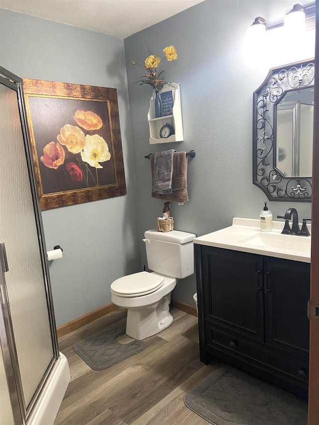 full bathroom with vanity, wood finished floors, baseboards, a stall shower, and toilet