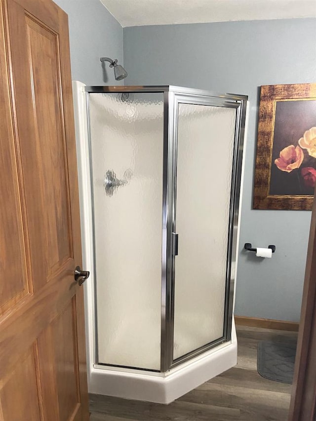 bathroom featuring wood finished floors and a stall shower