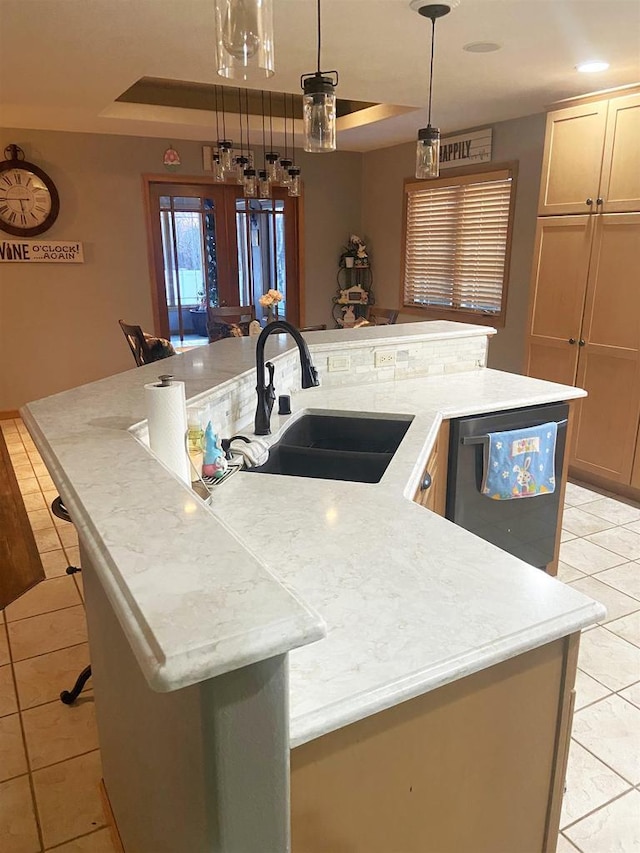 kitchen with light countertops, light tile patterned floors, stainless steel dishwasher, a large island, and a sink