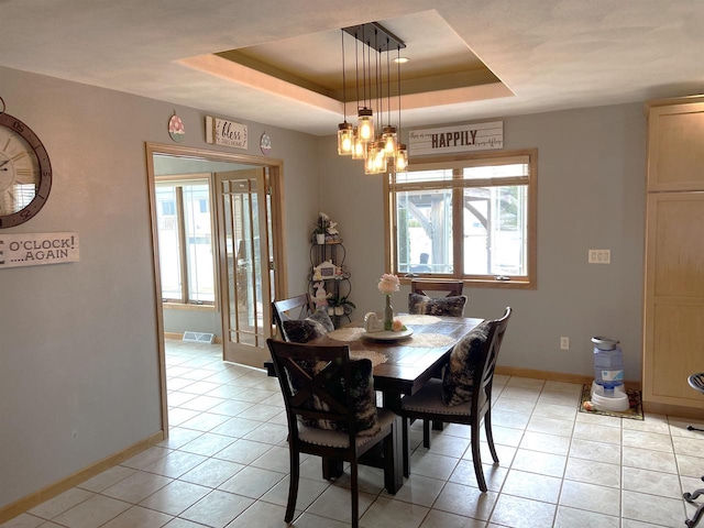 dining area with a tray ceiling, light tile patterned floors, visible vents, and baseboards