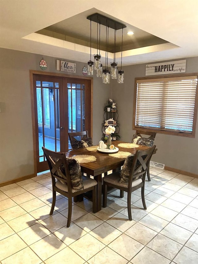 dining space featuring french doors, a raised ceiling, baseboards, and light tile patterned flooring