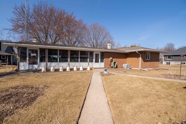 view of front of property featuring a front yard, a sunroom, and a chimney