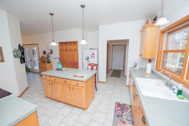 kitchen featuring a sink, light countertops, hanging light fixtures, and light brown cabinetry