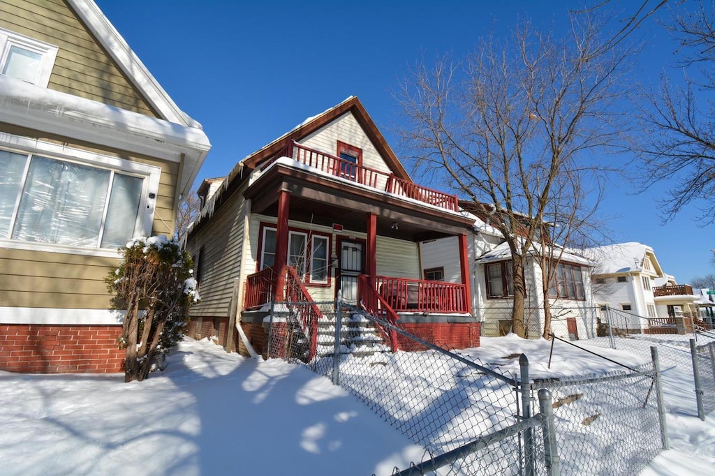 view of front of property with a fenced front yard, a balcony, and a porch