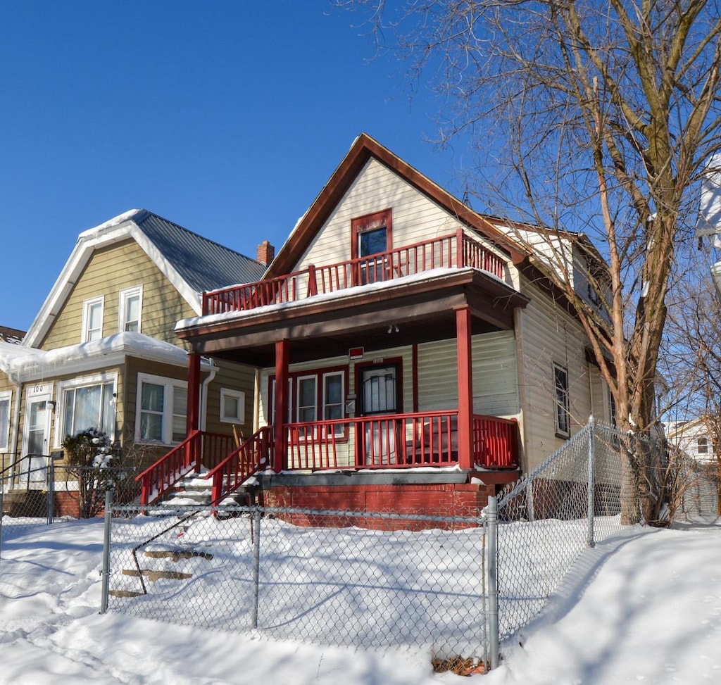 view of front facade with a balcony, covered porch, and a fenced front yard