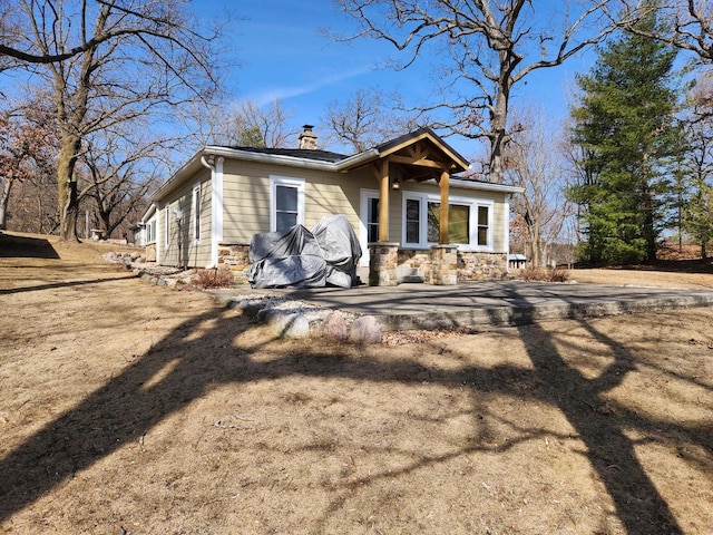 view of front of house featuring stone siding, driveway, and a chimney