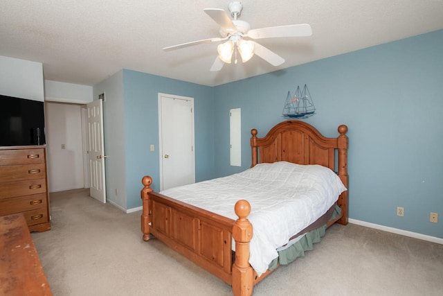 bedroom featuring baseboards, light colored carpet, a ceiling fan, and a textured ceiling