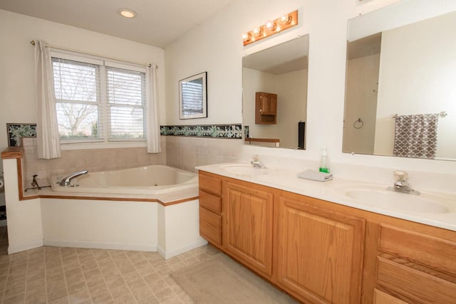 full bath featuring a garden tub, recessed lighting, double vanity, and a sink