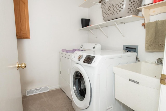 clothes washing area featuring visible vents, washer and clothes dryer, a sink, baseboards, and laundry area