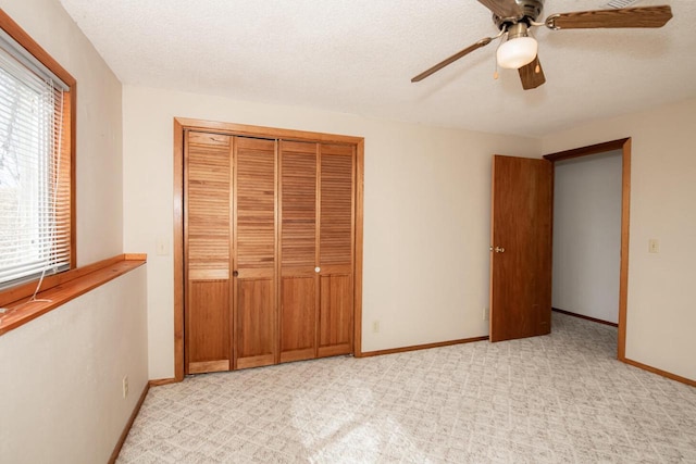 unfurnished bedroom with baseboards, light carpet, a closet, a textured ceiling, and a ceiling fan