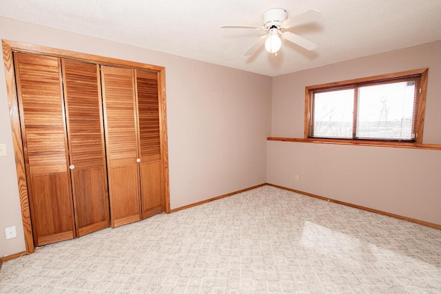 unfurnished bedroom featuring a closet, light carpet, baseboards, and ceiling fan