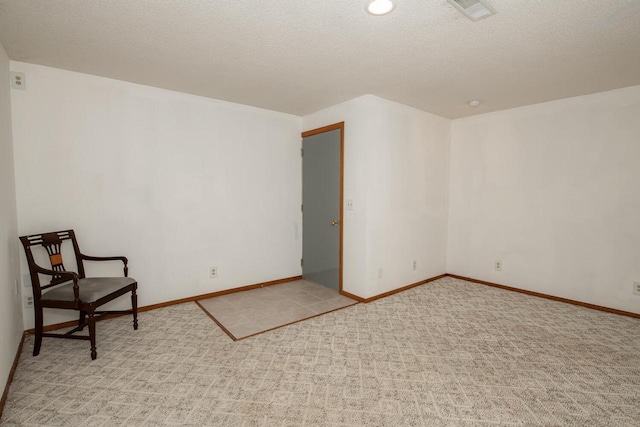 interior space with visible vents, light colored carpet, a textured ceiling, and baseboards