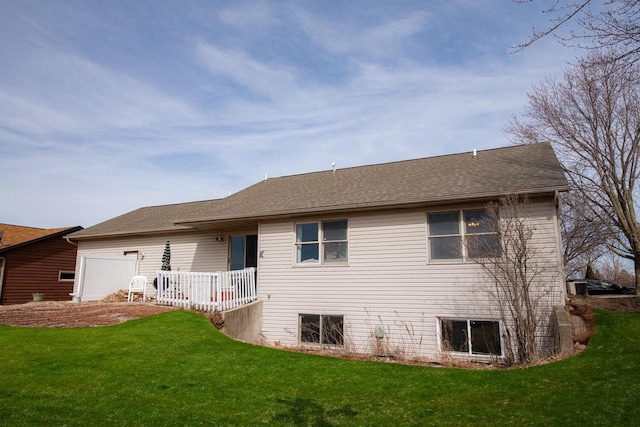 rear view of property with a lawn and roof with shingles