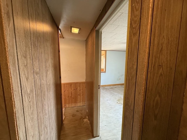 corridor featuring wooden walls and wainscoting