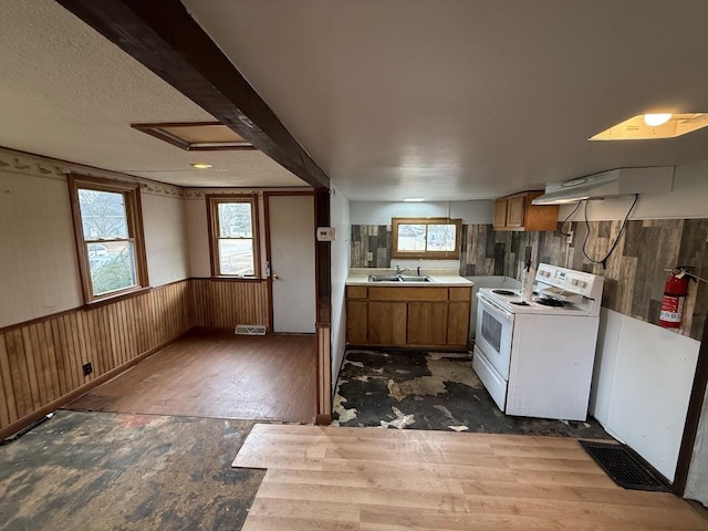 kitchen featuring brown cabinetry, washer / dryer, a sink, light countertops, and wainscoting