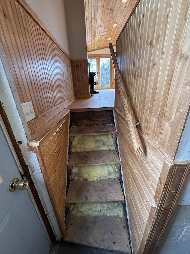 staircase featuring wooden walls, wood ceiling, and vaulted ceiling