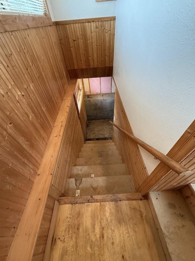 stairs featuring wainscoting and wood walls