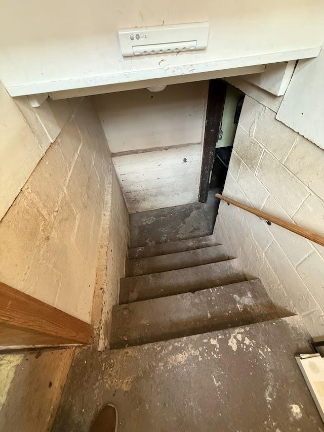 staircase featuring concrete block wall