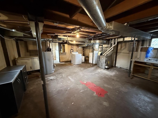 basement featuring heating unit, water heater, and washer and clothes dryer