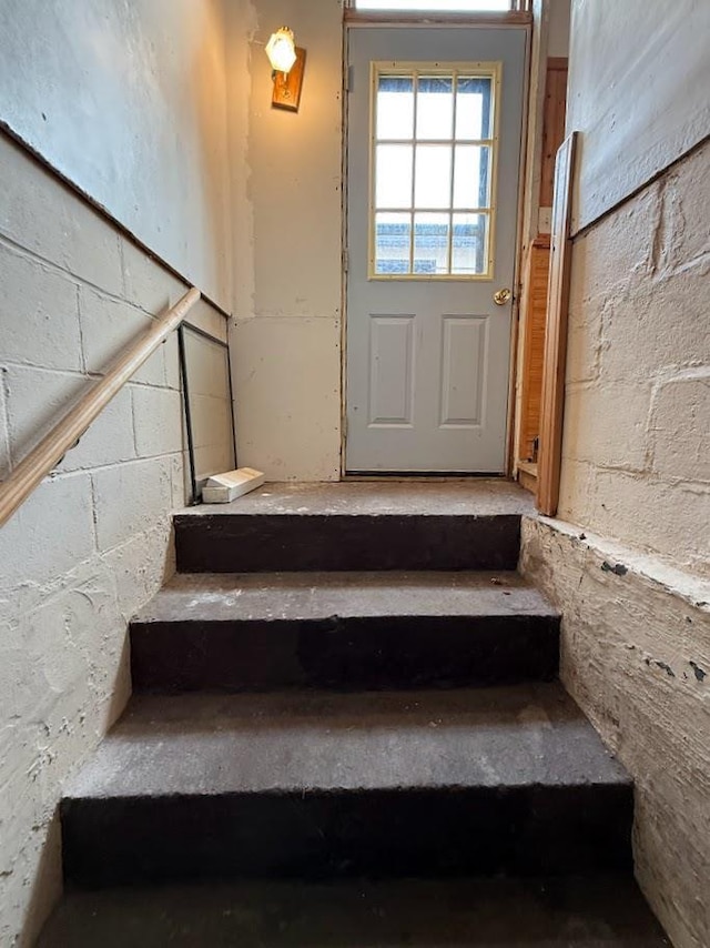 staircase featuring concrete block wall