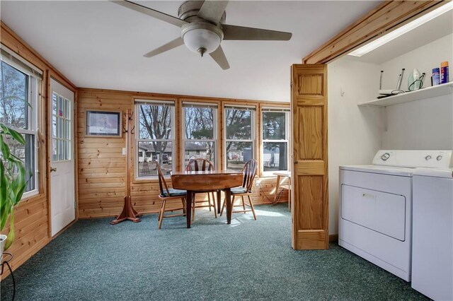 clothes washing area featuring laundry area, wood walls, carpet floors, and separate washer and dryer
