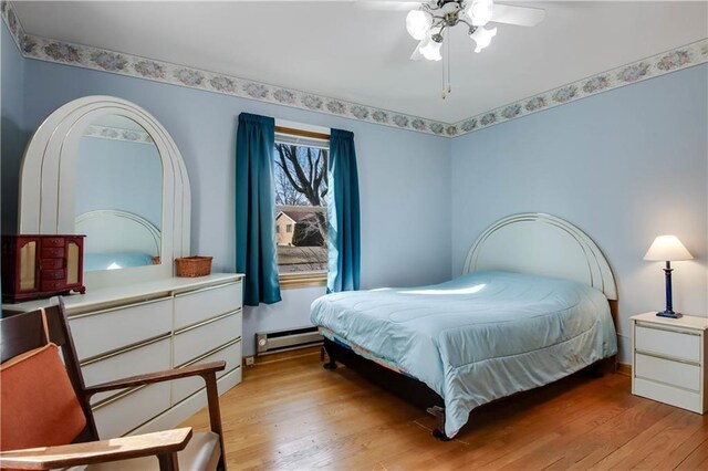 bedroom with a baseboard heating unit, a ceiling fan, and light wood-type flooring