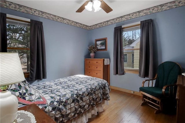 bedroom with a ceiling fan, baseboards, and wood-type flooring