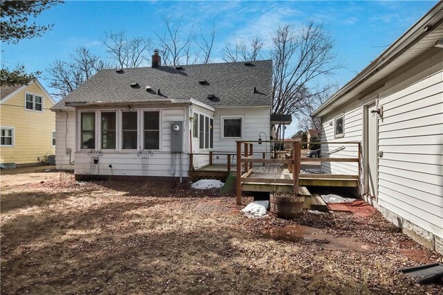 back of house with roof with shingles and a wooden deck