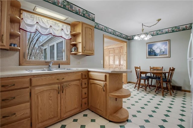 kitchen featuring light floors, open shelves, a peninsula, a sink, and light countertops