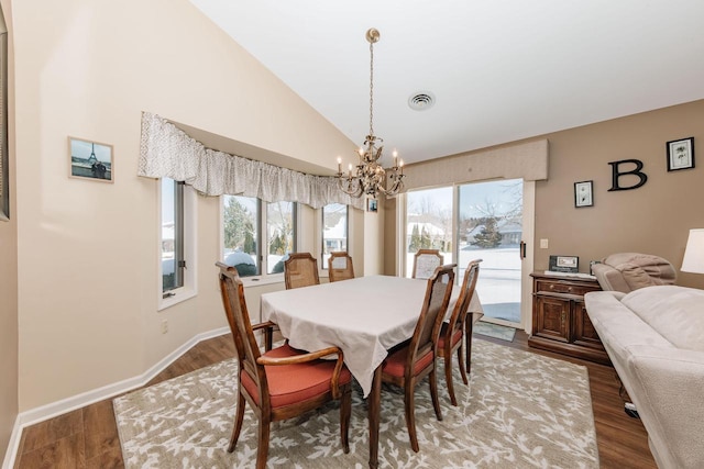 dining room with wood finished floors, visible vents, baseboards, vaulted ceiling, and a notable chandelier