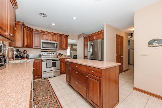 kitchen featuring a sink, a center island, stainless steel appliances, light countertops, and light tile patterned floors