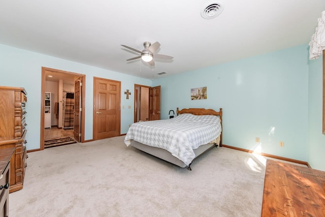 bedroom with visible vents, light carpet, a ceiling fan, ensuite bathroom, and baseboards